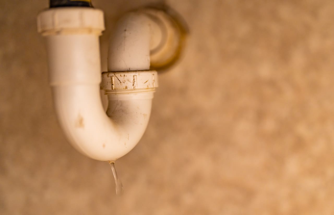Water leaking from the bottom of a white sink trap