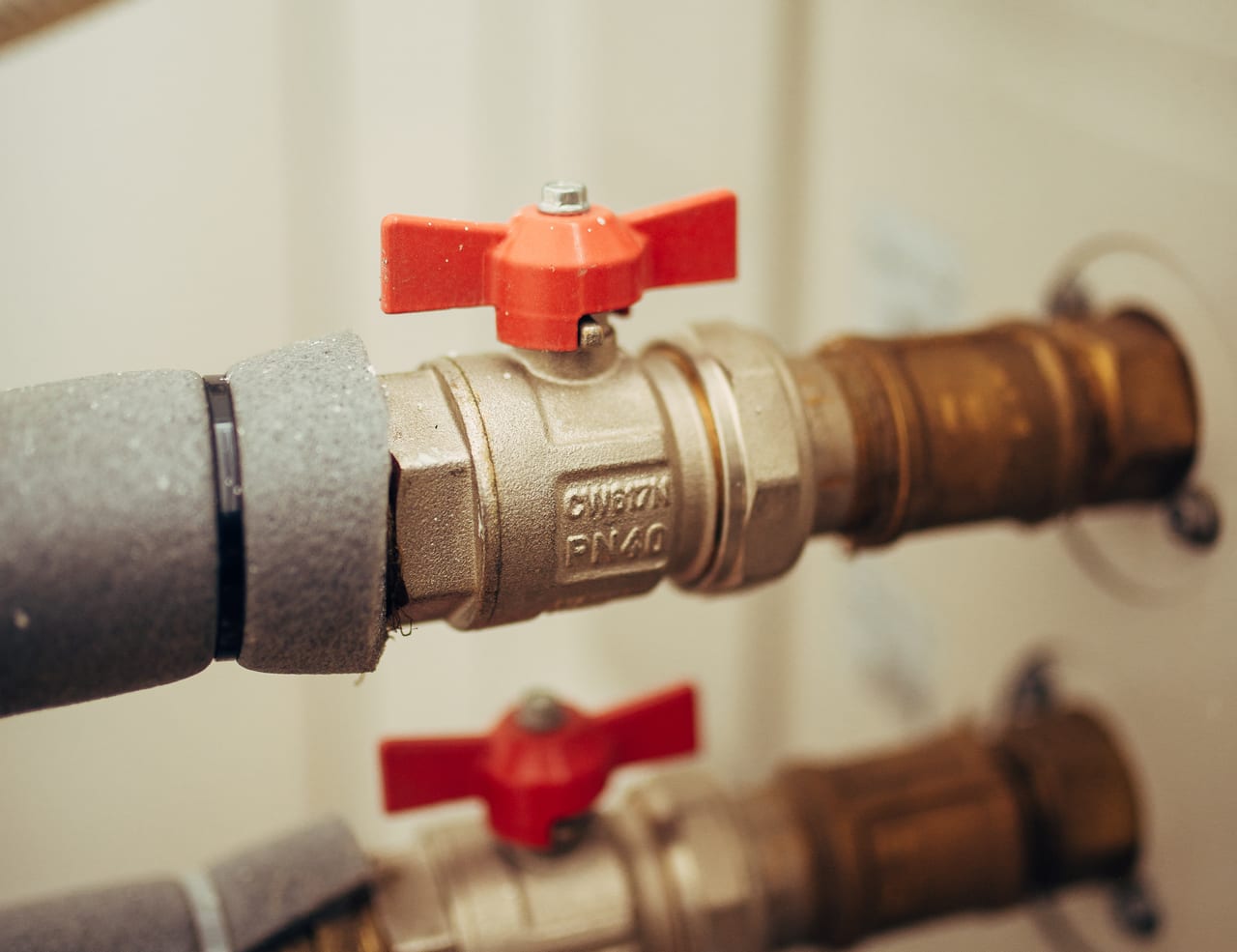 Red-handled isolation valves connecting insulated plumbing lines